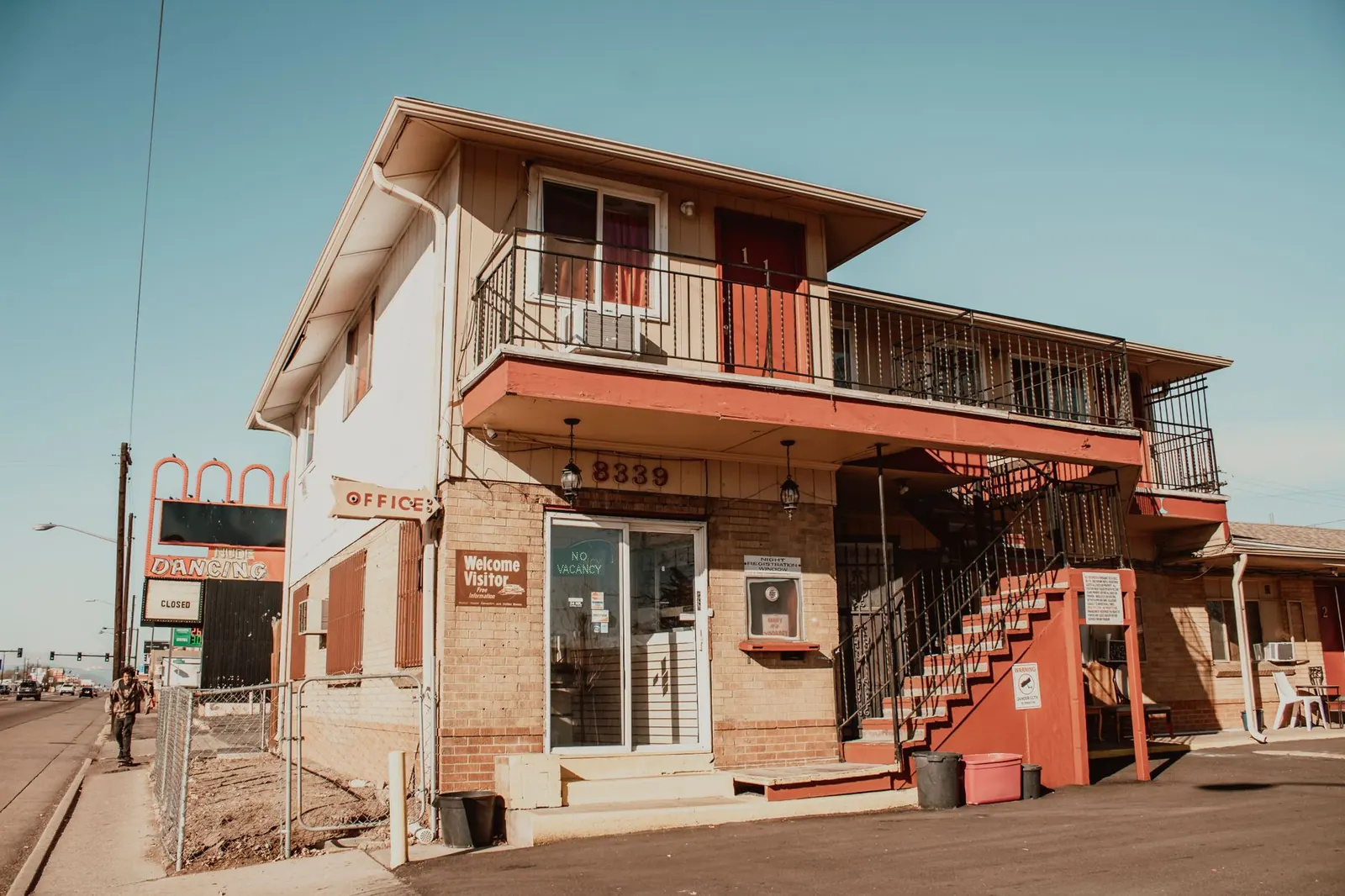 View of a vintage two-story motel with signage and stairs under clear blue skies in Denver.