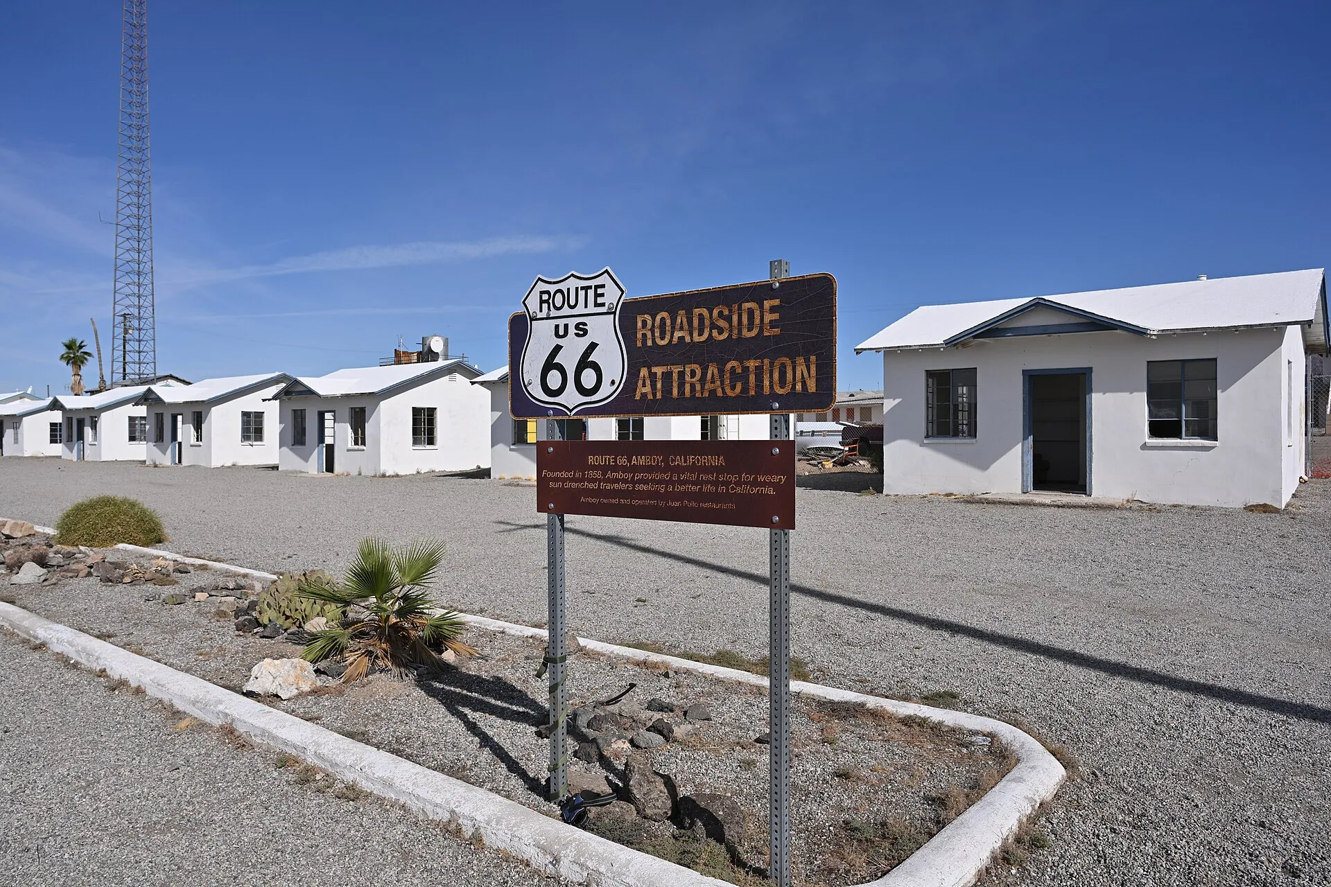 A sign designating this a Route 66 Roadside Attraction. Behind the sign are the individual cabins that made up the historic Roy's Motel. 87520 National Trails Highway, Amboy, California 92304. USA Travel: Roadside Accessibility Checklist