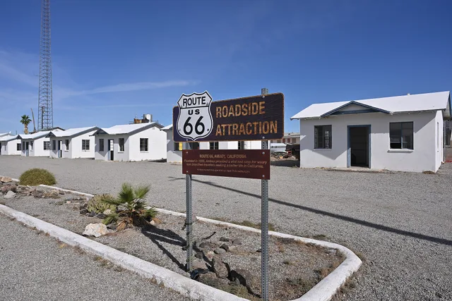 A sign designating this a Route 66 Roadside Attraction. Behind the sign are the individual cabins that made up the historic Roy's Motel. 87520 National Trails Highway, Amboy, California 92304. USA Travel: Roadside Accessibility Checklist