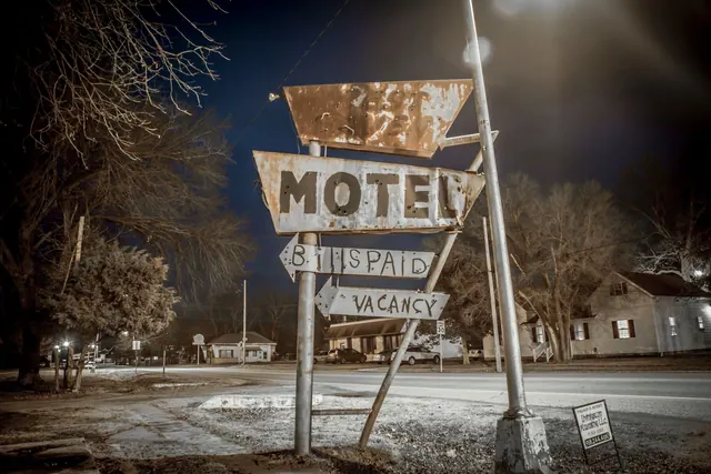 A vintage motel sign captured during nighttime on an empty urban street.