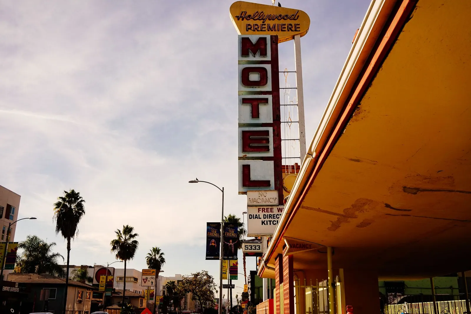 Iconic Hollywood Premiere motel sign against a California sky, framed by palm trees.