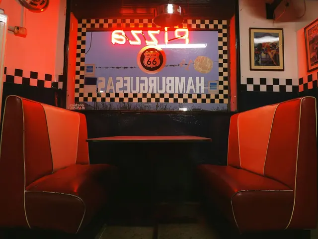 Vintage diner booth with a Route 66 neon sign in a classic retro interior setting.