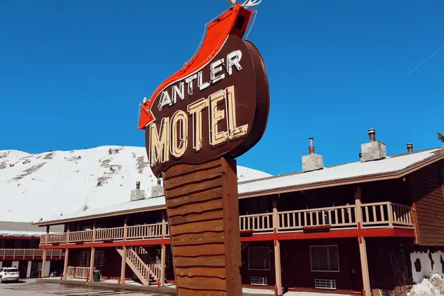 Iconic Antler Motel sign against snowy mountain backdrop in Jackson, Wyoming.
